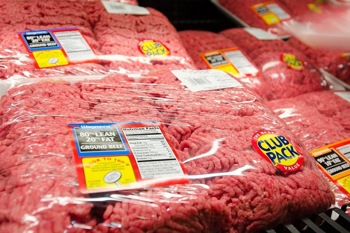 Pacotes de carne moída bovina embalados em plástico em gôndola refrigerada, com rótulos de 80% e 90% de carne magra