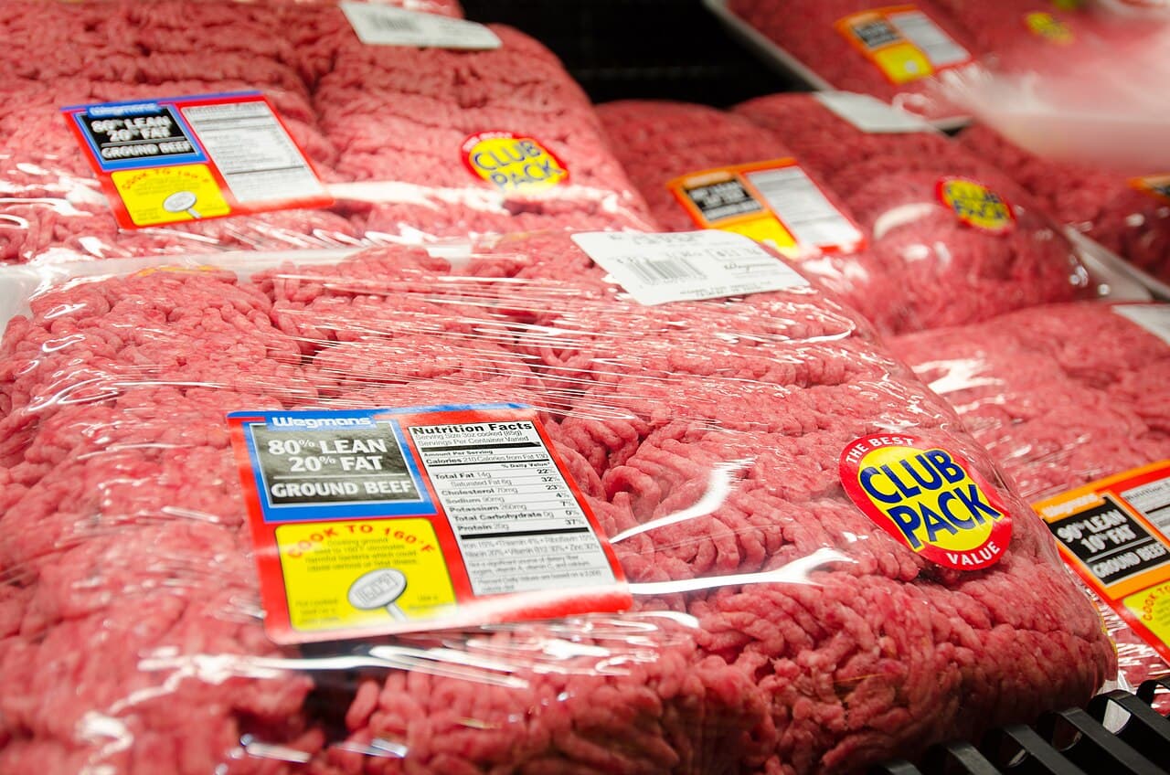 Pacotes de carne moída bovina embalados em plástico em gôndola refrigerada, com rótulos de 80% e 90% de carne magra