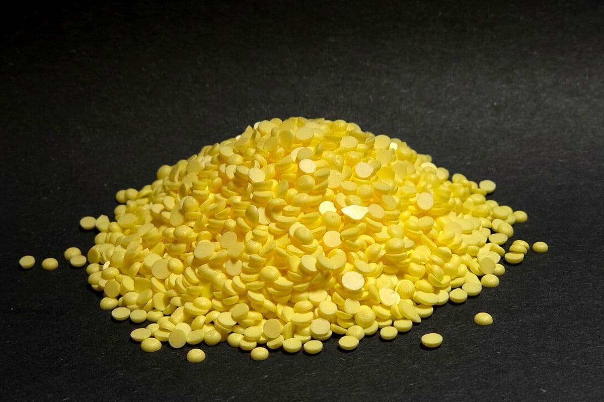Monte de pastilhas amarelas de enxofre sobre fundo preto