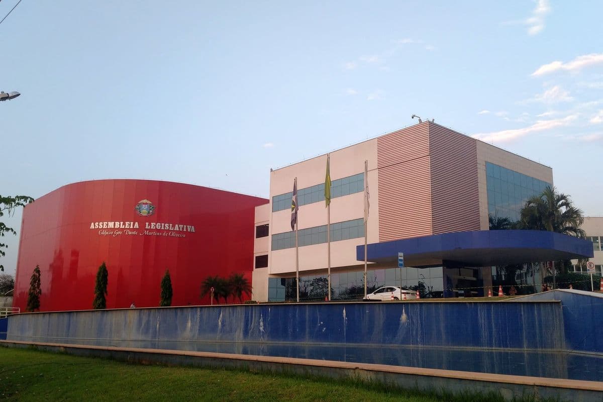 Fachada da Assembleia Legislativa de Mato Grosso, com bloco vermelho curvo e prédio de vidro