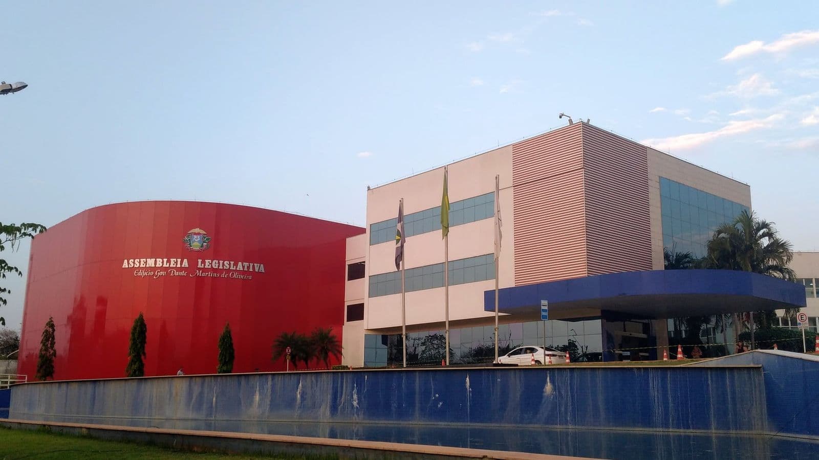 Fachada da Assembleia Legislativa de Mato Grosso, com bloco vermelho curvo e prédio de vidro
