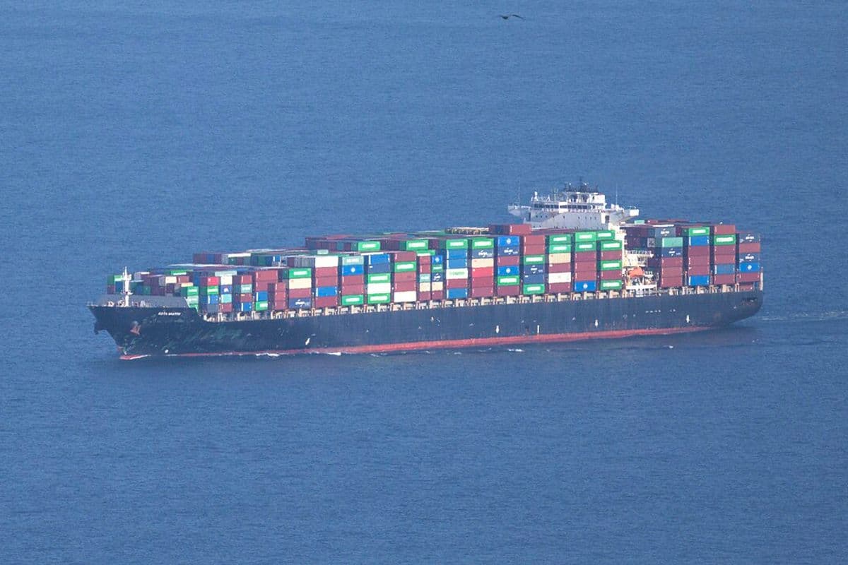 Navio porta-contêineres carregado de contêineres coloridos navega em mar azul