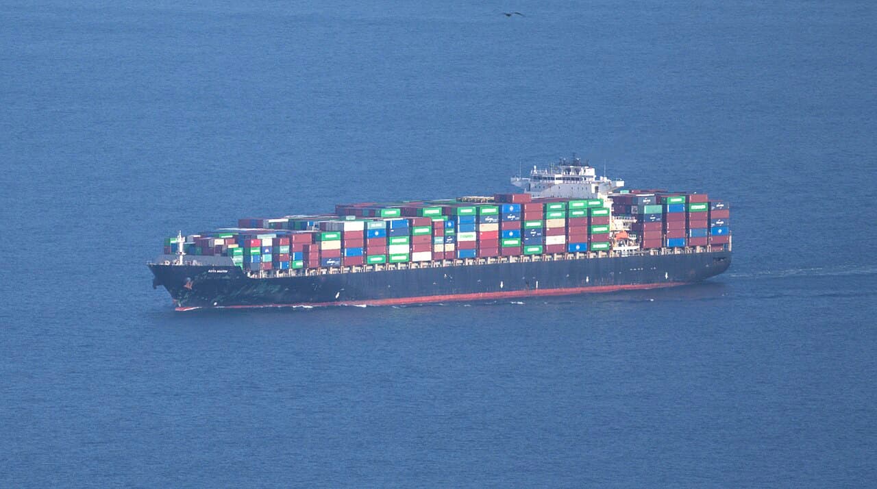 Navio porta-contêineres carregado de contêineres coloridos navega em mar azul