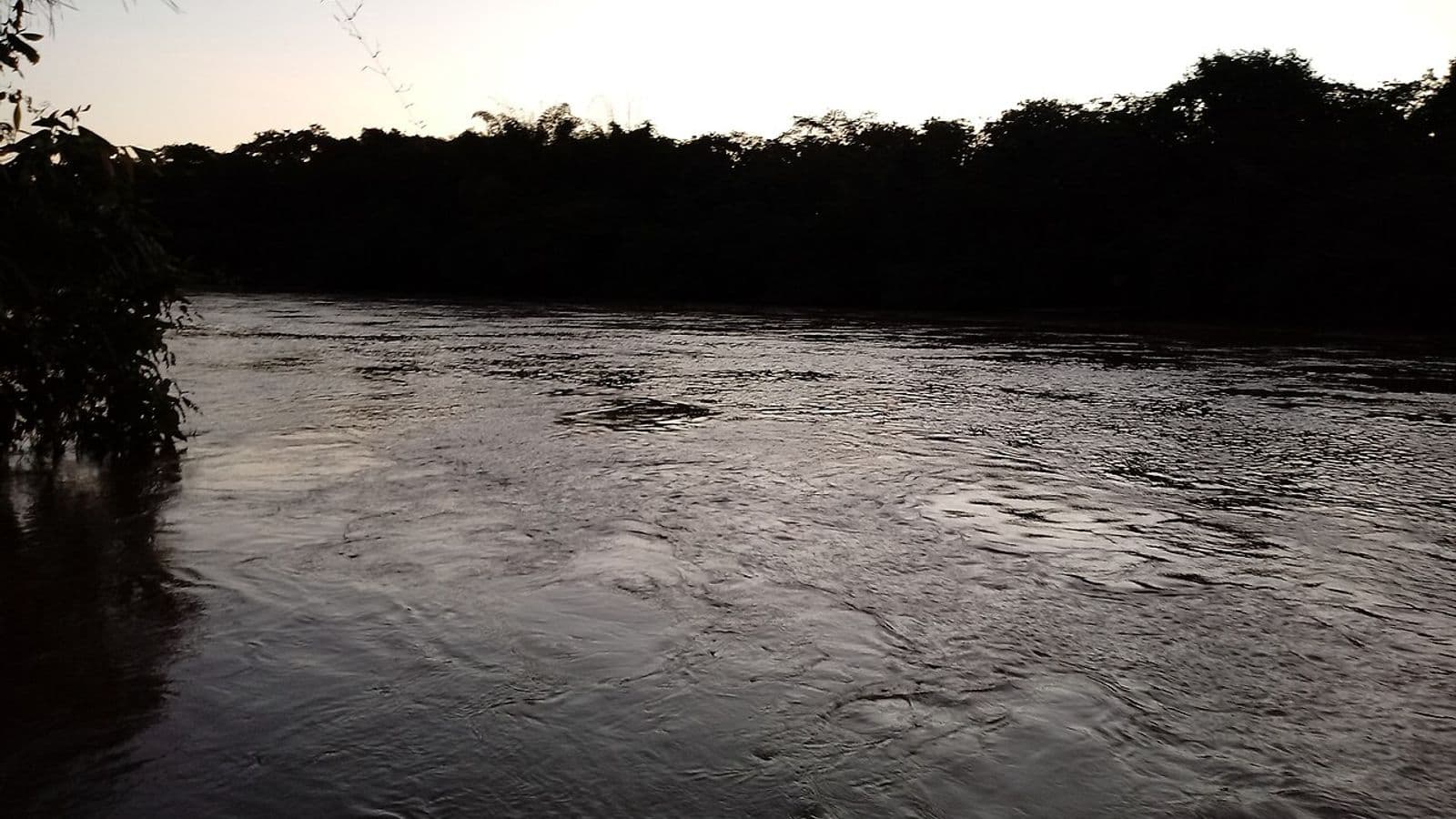 Rio Taquari com correnteza, ao entardecer, entre margens de mata ciliar escura