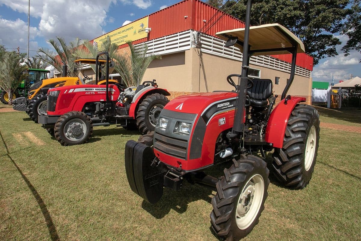 Tratores vermelhos estacionados no gramado de uma feira agrícola