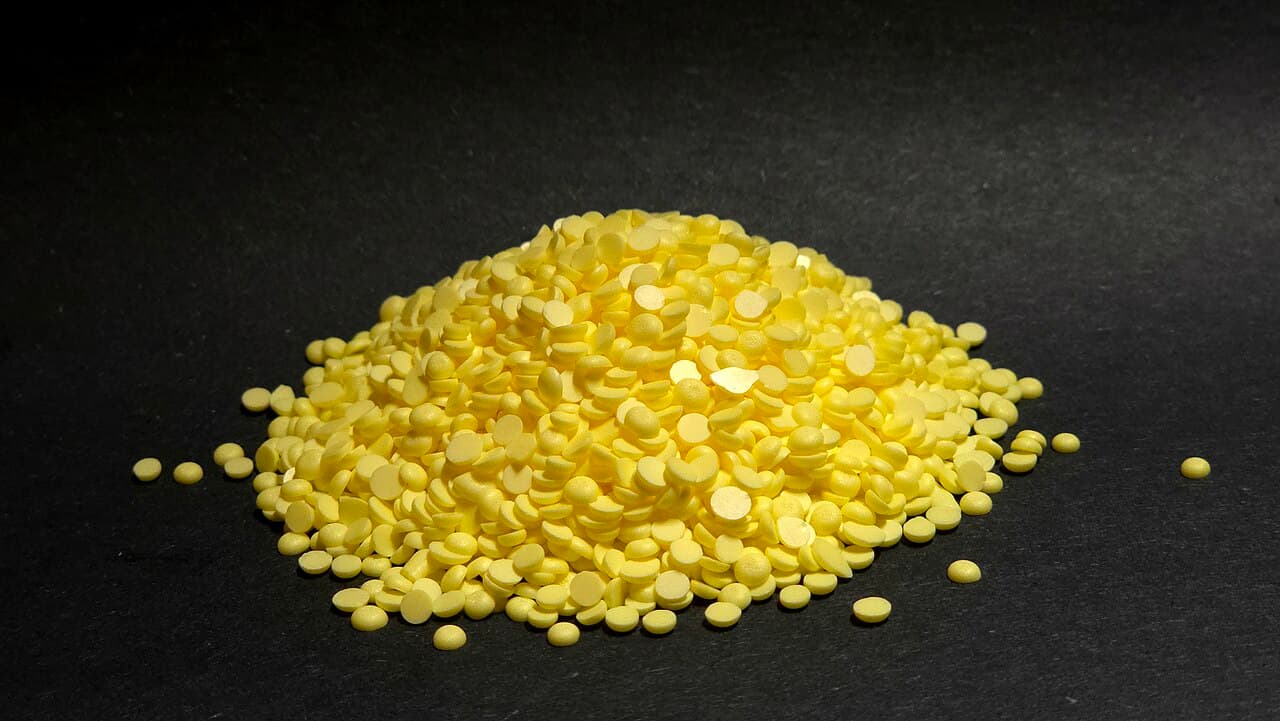 Monte de pastilhas amarelas de enxofre sobre fundo preto